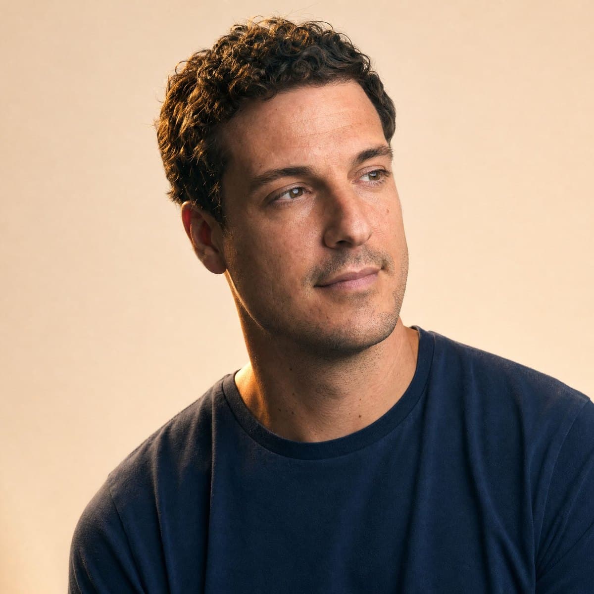 A calm man in his thirties in a navy t-shirt, glancing aside