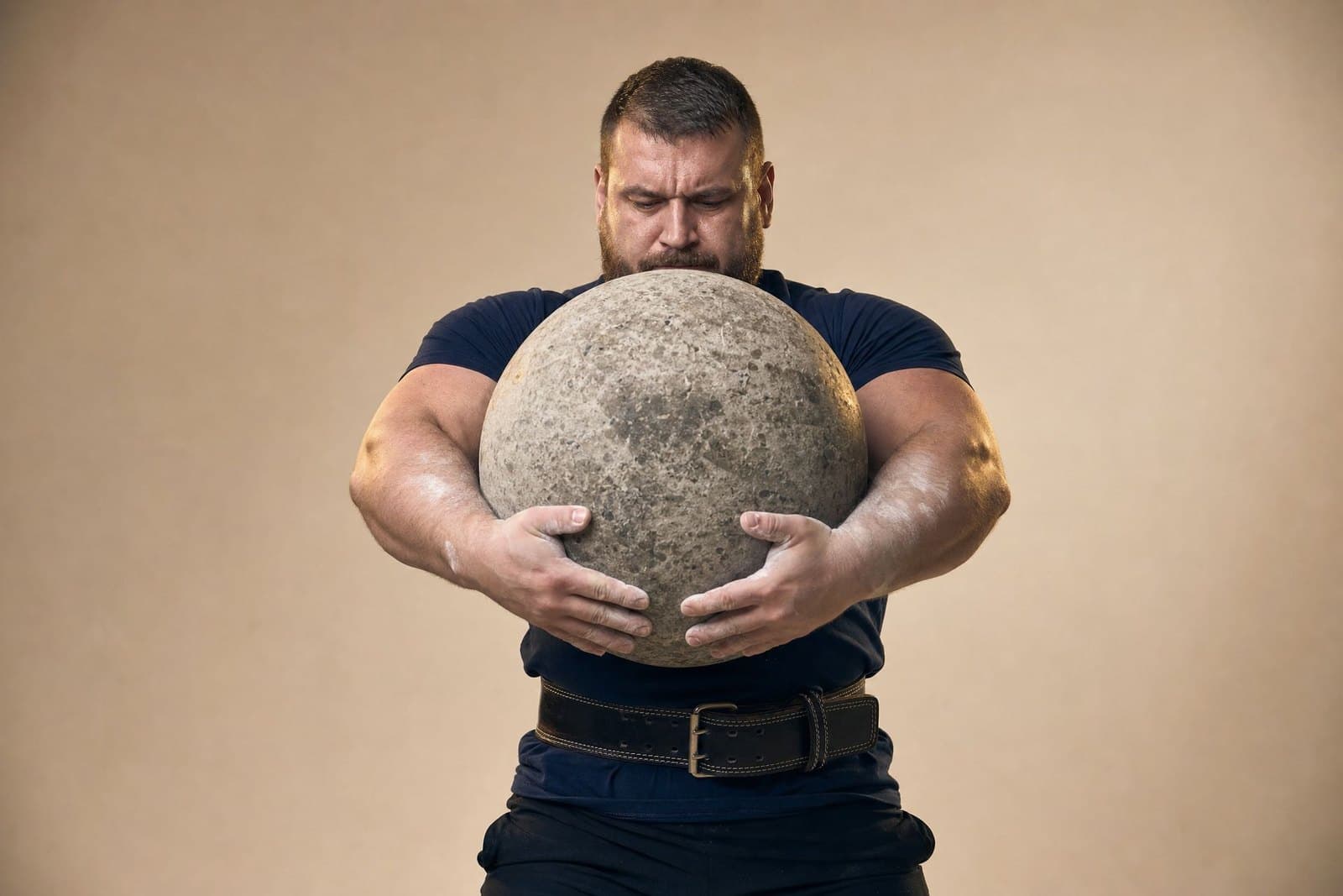 A strongman lifting an atlas stone to his chest