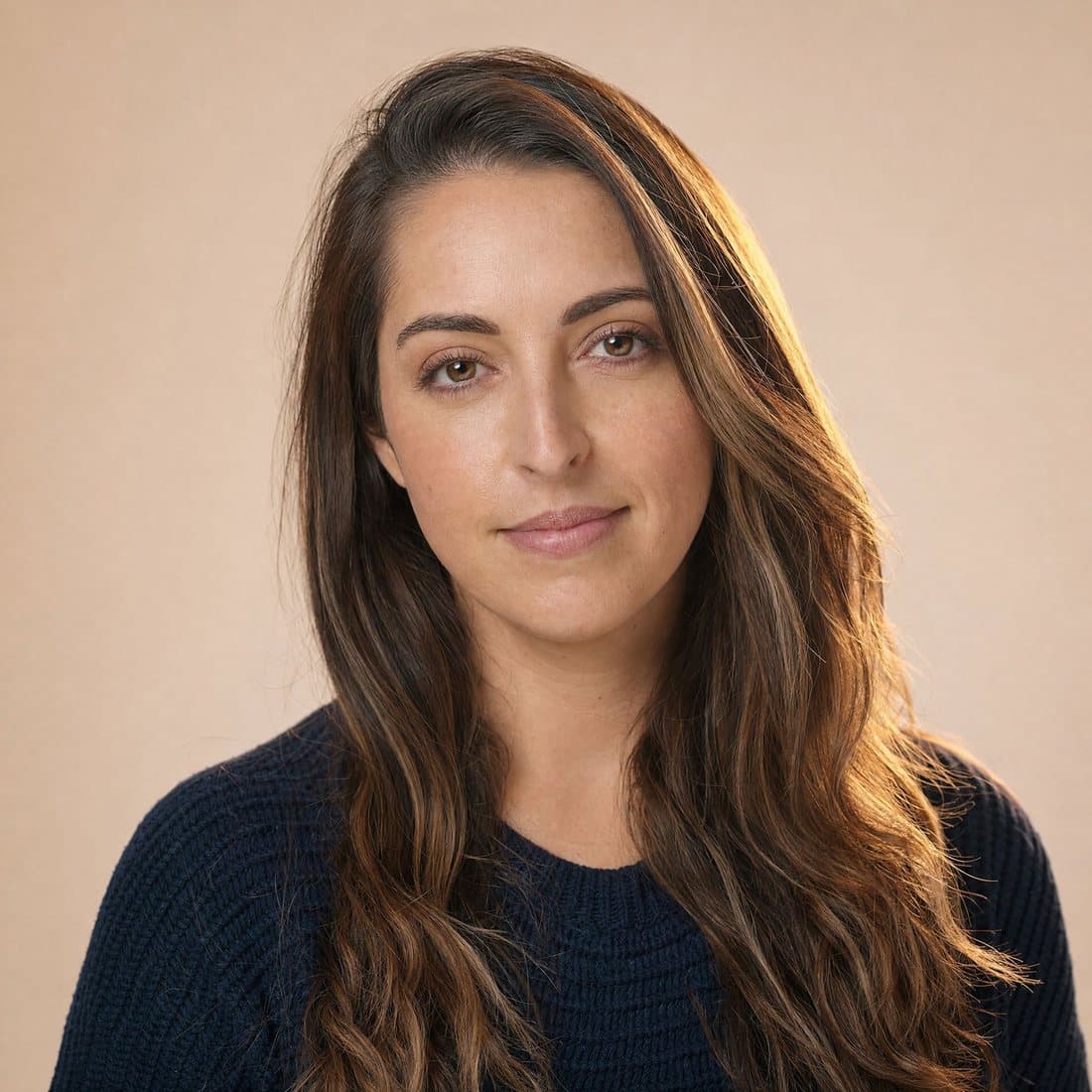 A calm woman in her early thirties in a navy knit